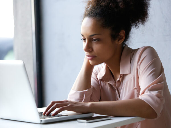 Close up portrait of a young black woman looking at laptop