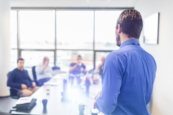 Business Presentation On Corporate Meeting. Business man making a presentation at office. Business executive delivering a presentation to his colleagues during meeting or in-house business training, explaining business plans to his employees.